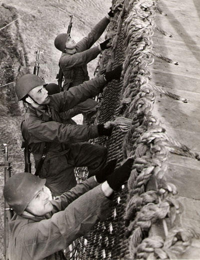 U.S. Navy photograph showing men climbing a rope wall